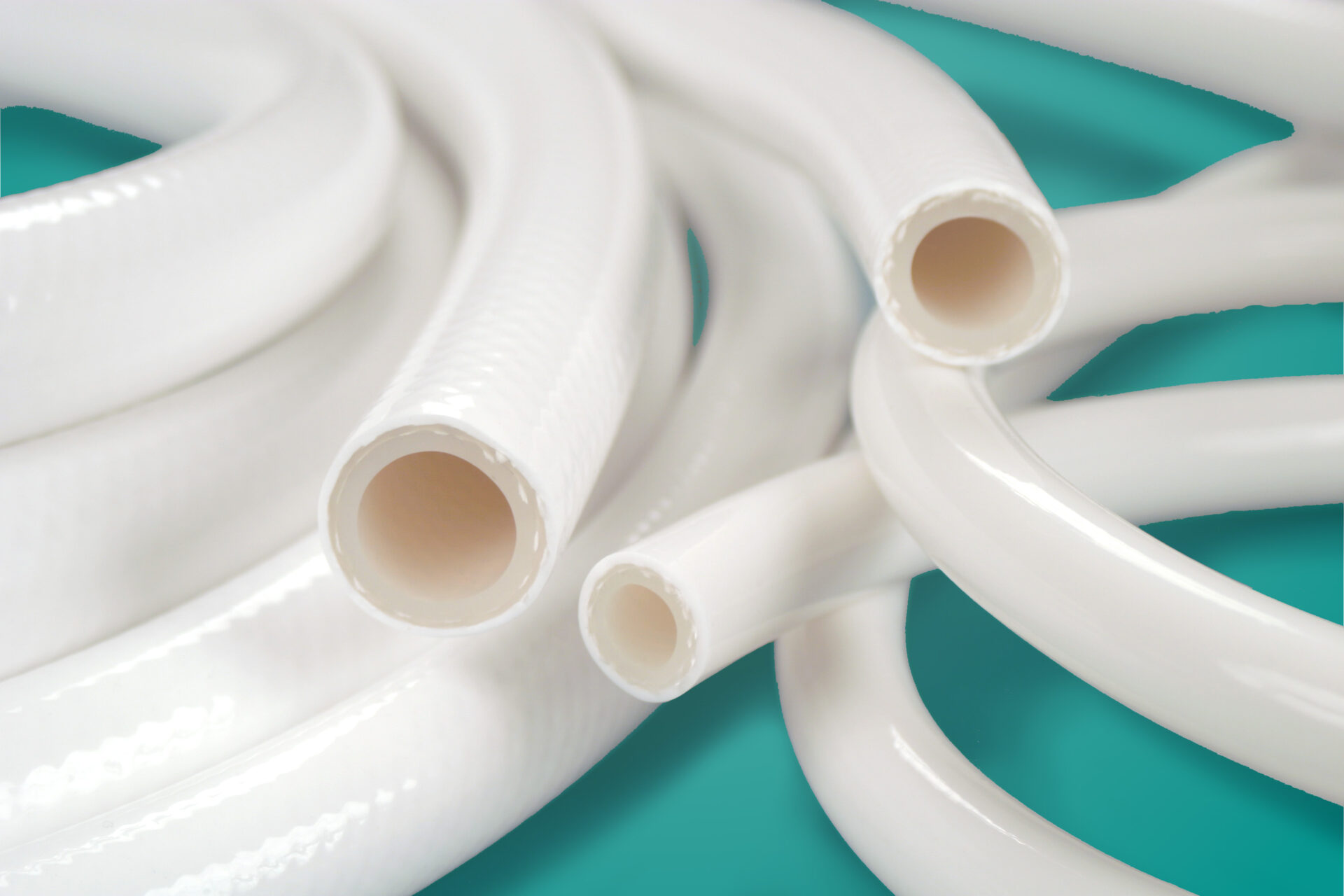 Close up image of APSH-DB tubing coil with three sizes of tubing ends on a teal background